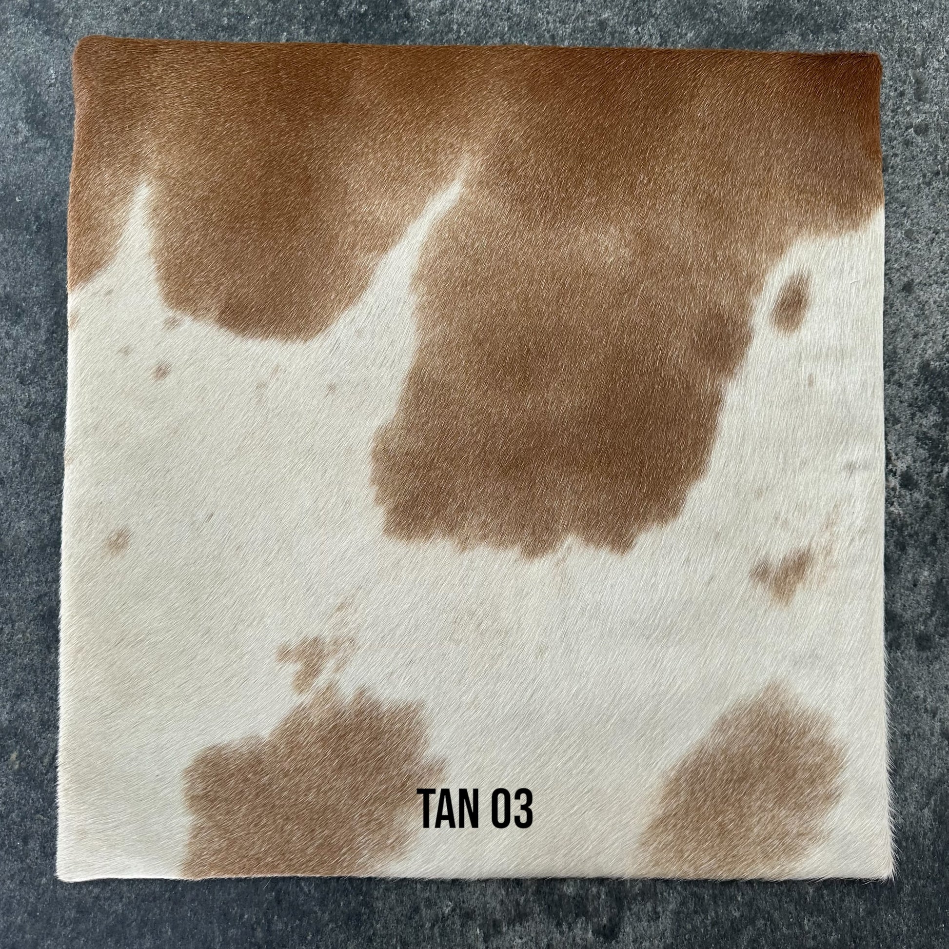 Tan and white cowhide cushion