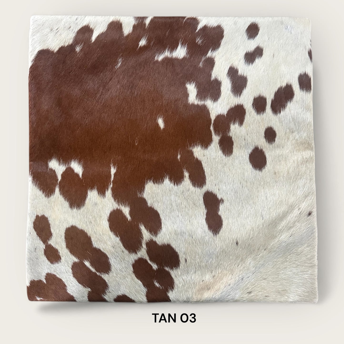 Tan and white cowhide cushion
